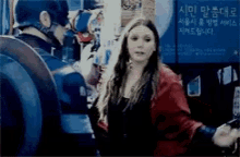 a woman in a red jacket stands next to a man in a captain america uniform