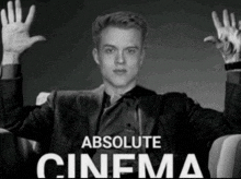 a black and white photo of a man with his hands in the air and the words absolute cinema behind him