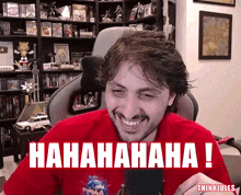 a man in a red shirt is laughing in front of a sign that says hahahaha
