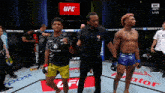 two fighters are standing on a ufc ring with a referee