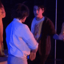 a man is standing next to another man in a dark room .
