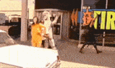 a woman is walking down the street in front of a store that says all tire