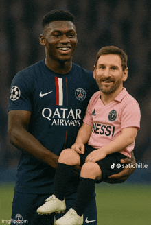 a man in a qatar airways shirt is holding a smaller man