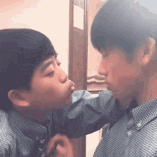 two boys are kissing each other on the cheek in front of a mirror