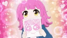 a girl with pink hair is holding a piece of paper with a drawing of a face on it