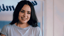 a woman is smiling and looking at the camera while wearing a grey t-shirt .