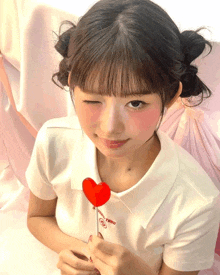 a girl holding a heart shaped lollipop that says pink toro