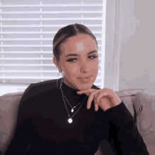 a woman wearing a black turtleneck necklace and hoop earrings