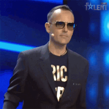 a man wearing sunglasses and a black t-shirt that says ' ic ' on it