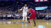 two basketball players are playing a game of basketball on a court with a sign that says homeland in the background .