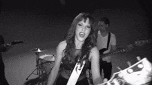 a black and white photo of a woman singing and playing a guitar in a band