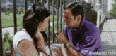 a man in a purple shirt talks to a woman in a white shirt