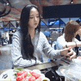 a woman in a sweater sits at a table with a plate of food and a sign that says ' happy '