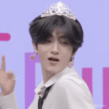 a boy wearing a tiara and earrings is holding a glass .