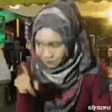 a woman wearing a hijab giving a thumbs up sign