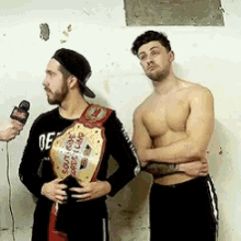 two men are standing next to each other with one wearing a south coast wrestling championship belt