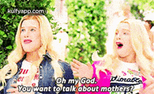 two blonde girls are standing next to each other and one of them is talking to the other .
