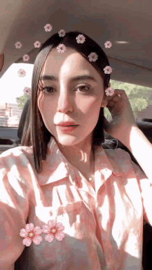 a woman in a pink shirt with flowers on her hair