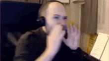 a man wearing headphones is playing a musical instrument while sitting at a desk .