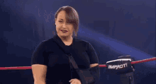 a woman with a cast on her arm is standing in a wrestling ring talking to another woman .