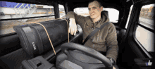 a man is sitting in a car with a sony speaker in the back seat