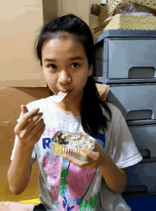 a girl wearing a shirt with the letter r on it is eating something