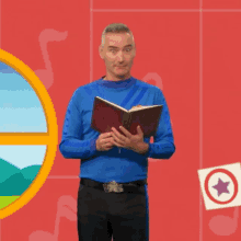 a man in a blue shirt is holding a book in front of a red background