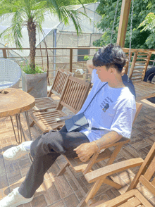 a man wearing a white t-shirt that says ' snoopy ' on it sits on a chair