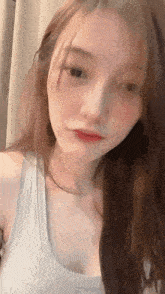 a close up of a woman wearing a white tank top .