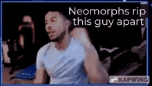 a man in a white shirt is sitting in front of a screen that says neomorphs rip this guy apart