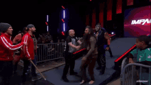 a referee is standing in front of a wrestling ring with the word impact on it