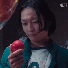 a woman in a green jacket is holding a red ball in her hand with a netflix logo in the background