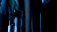 a person is holding a gun in a dark room with a blue light behind them .