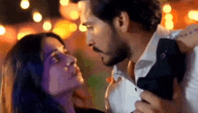 a man and a woman are kissing each other in front of a crowd of people .