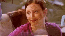 a woman in a purple sweater is sitting at a table with a cup of coffee in front of her .
