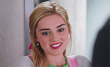 a close up of a woman 's face smiling while wearing a pink and green apron .