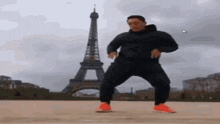 a man in sunglasses is dancing in front of the eiffel tower in paris .