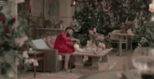 a man in a red sweater is sitting on a couch on a patio .