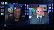 a man in a suit and tie is talking to another man on a television screen .