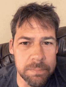 a man with a beard and a blue shirt looks at the camera
