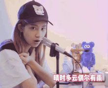 a woman wearing a baseball cap and headphones stands in front of a microphone