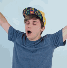 a young man wearing a blue shirt and a hat with pokemon on it