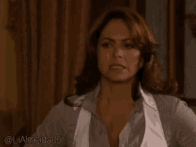 a woman wearing a white vest and a striped shirt is standing in a room .