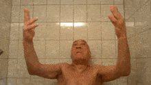 a man without a shirt is taking a shower and making a funny face