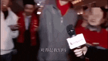 a person is holding a microphone in front of a crowd of people .