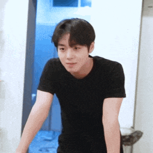 a young man wearing a black t-shirt is standing in a room with his arms outstretched