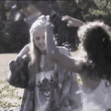 a girl wearing a shirt with a cat on it is being held by another girl