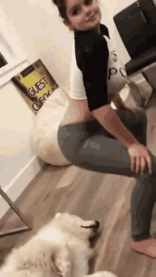 a woman is squatting down next to a dog and a guest check in sign