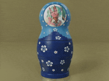 a blue green and orange nesting doll with a girl on it