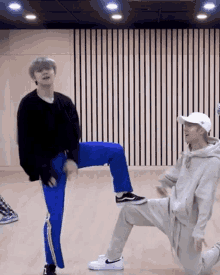 two men are dancing in a room with a striped wall .